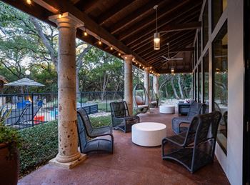 Covered outdoor lounge with hanging chairs and pool views